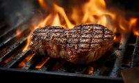 Juicy grilled beef steak with grill marks cooking over open flames on barbecue grate, smoke rising in dramatic lighting for food photography and menu design.