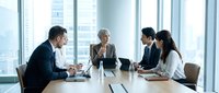 Young diverse business professionals in formal attire discussing strategy during corporate meeting in modern high-rise office with city skyline views. Use for business, teamwork, leadership content.
