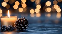 Glowing candle and pine cones with blurred golden bokeh lights creating cozy winter atmosphere on dark blue background. Perfect for holiday season designs.