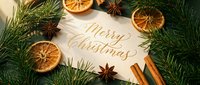 Merry Christmas calligraphy card surrounded by fir branches, dried orange slices, cinnamon sticks, and star anise on a dark green background.