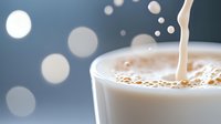 Pouring fresh milk creates dynamic splash in glass with creamy texture and bokeh light effect background, macro food photography for dairy advertising.