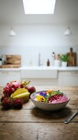 Smoothie bowl with dragon fruit, berries, and edible flowers on wooden counter in bright modern kitchen with white cabinetry and farmhouse sink.