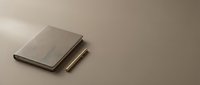 Minimalist workspace with closed notebooks and pen on neutral beige surface for professional business planning and creative writing projects.