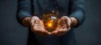 Glowing orange energy sphere floating between cupped hands against dark background, magical light particles and sparkles creating mystical atmosphere.