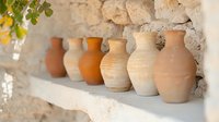 Handcrafted terracotta and clay vessels arranged on rustic stone shelf, showcasing traditional pottery techniques and earthy tones for home decor and artisan design projects.