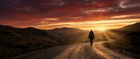 Silhouette of a lone traveler standing on a dusty mountain road at dramatic sunset with golden rays breaking through clouds and rugged terrain surrounding the path.