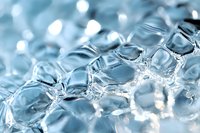 Macro shot of transparent bubble wrap with soft blue tint and bokeh highlights creating abstract pattern of geometric shapes and light reflections.