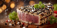Seared tuna steak with sesame crust and peppercorns on wooden board. Gourmet seafood dish with herbs and spices for fine dining restaurant menu.