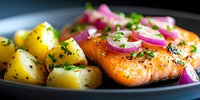 Grilled salmon fillet with boiled potatoes, red onion rings and fresh herbs on black plate, close up view of healthy dinner serving.