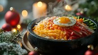 Korean mixed rice bowl with fried egg, fresh vegetables and spicy sauce served in stone bowl against festive Christmas decorations and glowing candles background.