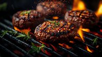Juicy beef burger patties grilling on barbecue with flames and rosemary sprigs, seasoned with herbs and spices for summer cookout.
