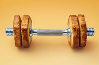 Creative fitness concept featuring dumbbell made with metal barbell and toasted bread slices as weights on orange background. Healthy lifestyle metaphor.