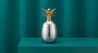 Metallic silver pineapple with golden crown on teal background for modern home decor and luxury kitchen design concepts.