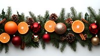 Fresh orange slices, red ornaments, pine cones and cinnamon sticks arranged with evergreen branches create festive winter holiday border decoration.