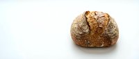 Freshly baked artisan sourdough bread loaf with golden brown crust on clean white background, isolated for bakery and food design projects.