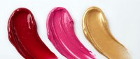 Glossy lipstick smears in red, pink, and gold on white background, showcasing vibrant cosmetic textures for beauty and makeup design.