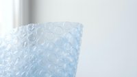 Blue bubble wrap packaging material with air-filled pockets for protective shipping and storage solutions in minimalist white interior setting.