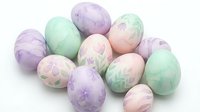 Pastel colored Easter eggs with delicate floral patterns in soft purple, green and pink hues isolated on white background for spring holiday decorations.