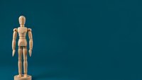 Wooden artist mannequin figure standing on teal background with copy space for creative design projects and artistic presentations.