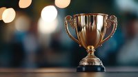 Golden trophy cup on dark background with soft bokeh lights, symbolizing achievement, victory and success in sports or business competition.