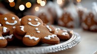 Smiling gingerbread men cookies arranged on vintage glass plate with festive bokeh lights in background, selective focus on decorated holiday treats.
