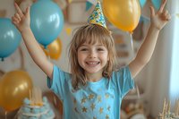 Happy young girl in party hat raising arms with joy at birthday celebration surrounded by blue and gold balloons, wearing turquoise t-shirt with stars pattern.