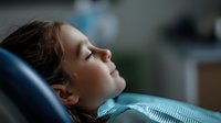 Young Caucasian woman patient relaxing with closed eyes during dental examination in modern clinic chair, peaceful healthcare experience.
