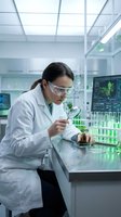 Female scientist examining plant samples with magnifying glass in modern laboratory for biotechnology research and agricultural development.