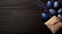 Blue Easter eggs with floral patterns and gift box on dark wooden background with pussy willow branches for spring holiday celebration and greeting cards.