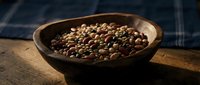 Roasted coffee beans in rustic wooden bowl on textured surface with dark blue fabric background for cafe branding and culinary design projects.