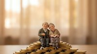 Elderly couple figurines sitting on stacks of golden coins representing retirement savings, financial planning and pension fund investment security.
