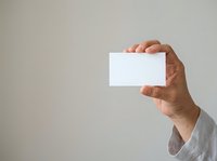 Male hand holding blank white card against neutral background for business branding and corporate identity mockup purposes.
