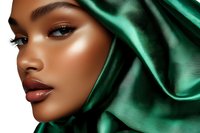 Young African American woman with glowing skin and professional makeup wearing emerald green silk head covering, side profile against dark background.