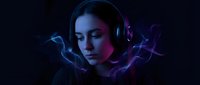 Young woman with headphones surrounded by colorful smoke in dramatic lighting for music and entertainment concepts.
