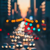 Blurred city street lights create colorful bokeh circles at dusk with warm orange and red glowing orbs against urban evening backdrop for atmospheric design.