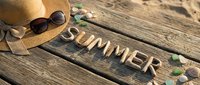 Summer word made of wooden letters on rustic boardwalk with straw hat, sunglasses, seashells, and sea glass for seasonal beach concepts.