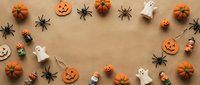 Halloween decorations arranged in circle frame on kraft paper background with pumpkins, ghosts, spiders and candy creating festive border for seasonal design projects.