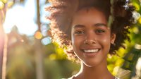 Young African American woman with curly hair smiling outdoors in natural sunlight with bokeh background for lifestyle and wellness content.