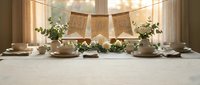 Elegant rustic table setting with white roses, eucalyptus greenery, candles, and burlap banner in warm natural light for wedding or event.