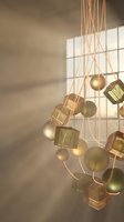 Modern pendant lighting fixture with geometric glass cubes and metallic spheres casting warm shadows through window light for contemporary interior design.