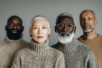 Diverse group of mature adults with silver hair wearing neutral knit sweaters against minimal background, representing inclusivity and aging gracefully.