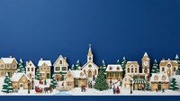 Miniature winter village with snow-covered buildings, church, evergreen trees, and festive figures on snowy ground against deep blue background for holiday decorations.
