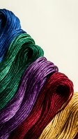 Colorful embroidery thread skeins arranged in rainbow pattern showing blue green purple red yellow cotton floss for needlework crafts and sewing projects.