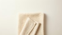 Natural beige waffle weave cotton towels folded on neutral background for bathroom decor and home textile design projects.