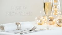 Elegant New Year table setting with champagne glass, silverware, white napkin, and golden bokeh ornaments, Happy New Year text on light background.