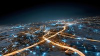 Aerial night view of illuminated city highways and digital network connections overlaid, representing smart urban infrastructure and technology integration.