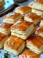 Golden flaky puff pastry squares with glossy caramelized tops arranged on baking sheet, freshly baked buttery layered pastries for bakery and culinary content.