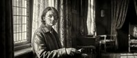 Young Caucasian man in historical period clothing sitting by window in vintage interior with dramatic lighting for educational or storytelling projects.