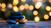Zen stones stacked on wooden surface against blurred golden bokeh lights creating peaceful spa atmosphere for wellness and meditation practices.