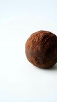 Chocolate truffle dusted with cocoa powder on white background for confectionery and dessert designs.